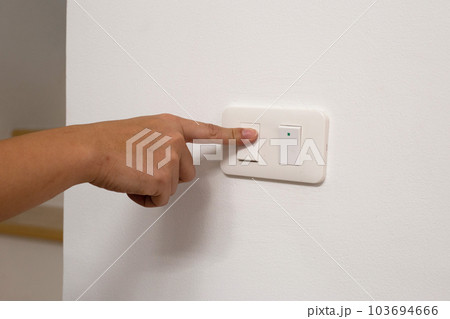 Hand turning off light switch 103694666