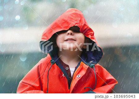 Happy boy, red raincoat and little child playing or having fun with the raindrops and outdoors. Smile, kid and looking up at the sky or enjoying rainfall and showers on bokeh background Happy boy, red raincoat and little child playing or having fun with the raindrops and outdoors. Smile, kid and looking up at the sky or enjoying rainfall and showers on bokeh background 103695043
