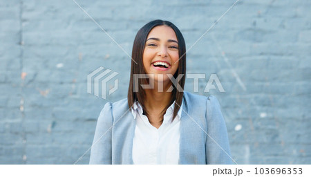 Cheerful woman laughing and giggling about something funny while standing outside against a grey wall with copy space. Happy businesswoman having fun and expressing positivity and a playful attitude 103696353