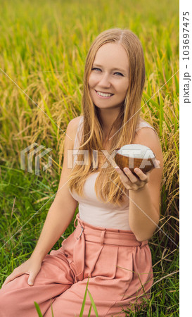 A woman is holding a cup of boiled rice in a wooden cup on the background of a ripe rice field VERTICAL FORMAT for Instagram mobile story or stories size. Mobile wallpaper 103697475