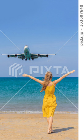Woman have fun on the beach watching the landing planes. Traveling on an airplane concept. Text space. Island Phuket in Thailand. Impressive paradise. Hot beach Mai Khao. Amazing landscape VERTICAL 103697648
