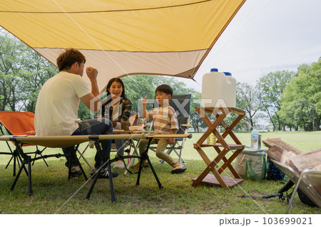 キャンプで家族団欒・タープの下でくつろぐ、ファミリーイメージ 103699021