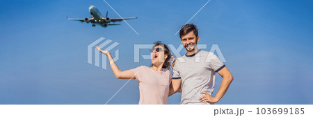 Man and woman tourists have fun on the beach watching the landing planes. Traveling on an airplane concept. Text space. Island Phuket in Thailand. Impressive paradise. Hot beach Mai Khao. Amazing 103699185