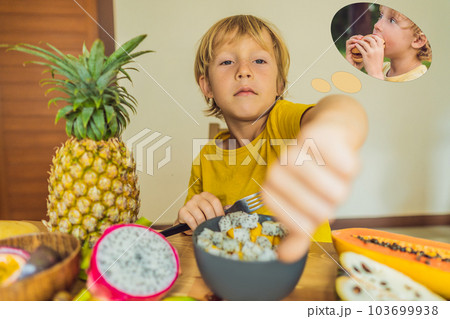 Boy eats fruit but dreams about hamburger. Harmful and healthy food for children. Child eating healthy snack. Vegetarian nutrition for kids. Vitamins for children. Junk food concept Boy eats fruit but dreams about hamburger. Harmful and healthy food for children. Child eating healthy snack. Vegetarian nutrition for kids. Vitamins for children. Junk food concept 103699938