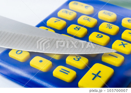 Knife blade placed on euro coin, calculator. Concept cutting rates, money business, crime. Macro. 103700007