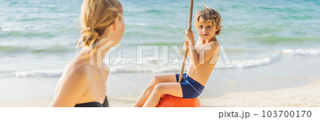 A boy on a swing on the beach. Mom and son spend time on the beach BANNER, LONG FORMAT A boy on a swing on the beach. Mom and son spend time on the beach BANNER, LONG FORMAT 103700170