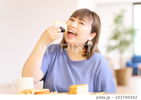 豪快にケーキを食べる若い女性 豪快にケーキを食べる若い女性 103700302