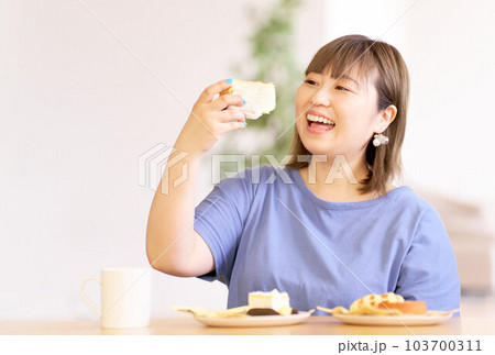 手にしたケーキを見つめる若い女性 103700311
