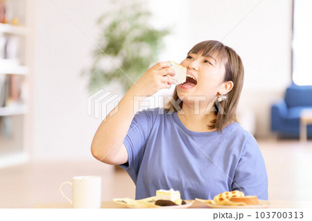 美味しそうにケーキを食べる若い女性 美味しそうにケーキを食べる若い女性 103700313