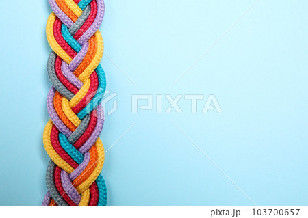 Top view of braided colorful ropes on light blue background, space for text. Unity concept 103700657