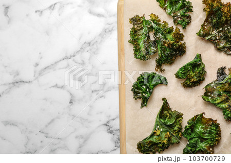 Tasty baked kale chips on marble table, top view. Space for text Tasty baked kale chips on marble table, top view. Space for text 103700729