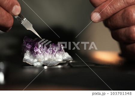 Professional jeweler working with beautiful amethyst at table, closeup 103701348