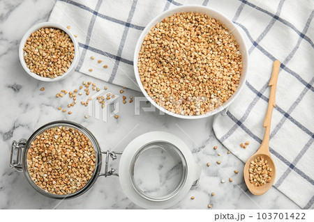 Uncooked green buckwheat grains on white marble table, flat lay Uncooked green buckwheat grains on white marble table, flat lay 103701422