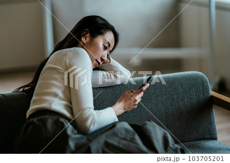 ソファーでごろごする女性 103705201