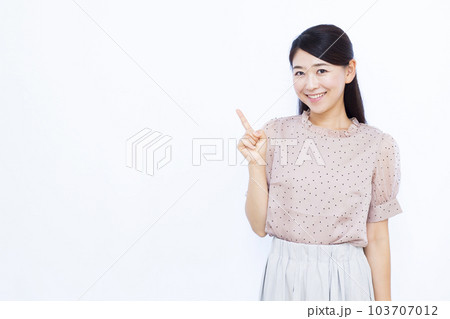 白い背景の前で人差し指をたてる30代の女性 103707012