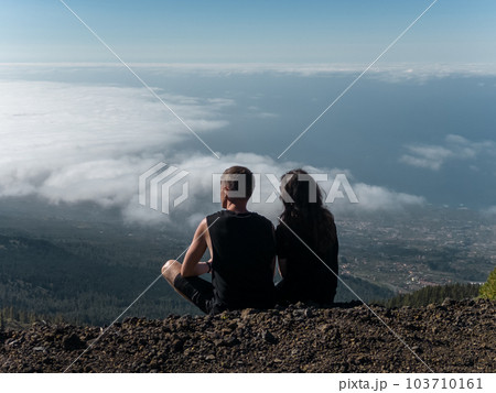 romantic lovely couple sitting on mountain top above clouds and looking on view romantic lovely couple sitting on mountain top above clouds and looking on view 103710161