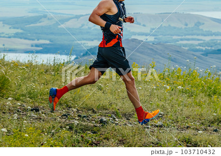 male runner running marathon trail race in background of mountains and lake, summer ultramarathon male runner running marathon trail race in background of mountains and lake, summer ultramarathon 103710432