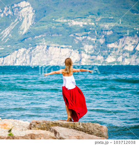 Woman in red dress staying at the lake 103712038