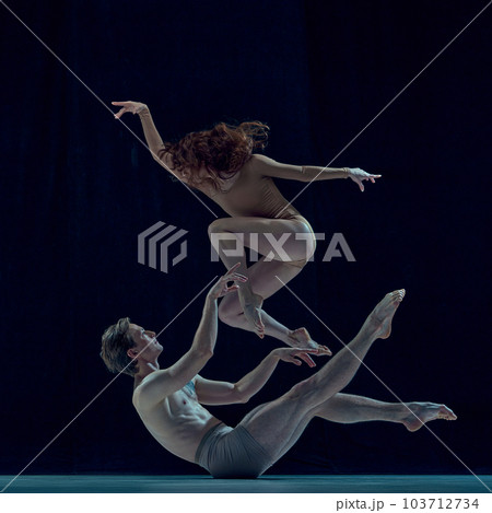 Beautiful, artistic, young couple, man and woman dancing ballet against blue studio background. Impressive art Beautiful, artistic, young couple, man and woman dancing ballet against blue studio background. Impressive art 103712734