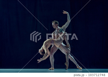 Muscular young man and beautiful woman, ballet dancers making artistic performance, dancing against blue studio background Muscular young man and beautiful woman, ballet dancers making artistic performance, dancing against blue studio background 103712748