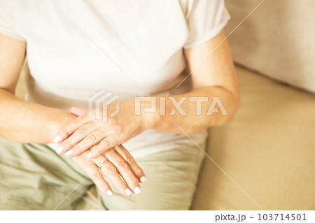 Close up of a senior woman appllying hand cosmetic cream at home. 103714501