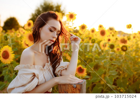 Beautiful woman in a dress in a field of sunflowers 103715024