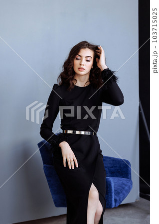 Woman in black dress sitting in a chair 103715025