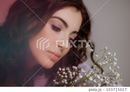 A brunette girl holds a bouquet of gypsophila flowers in her hands. 103715027