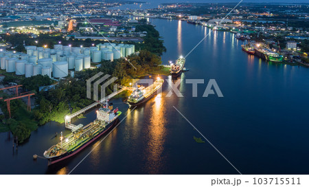 Aerial view oil storage tanks and tanker in river at night, Aerial view of oil storage tanks and tanker ship in the port town, Tanker ship in the port. Aerial view oil storage tanks and tanker in river at night, Aerial view of oil storage tanks and tanker ship in the port town, Tanker ship in the port. 103715511