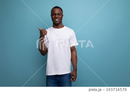 handsome 30s african man with short haircut in white t-shirt shows his hand towards space 103716570
