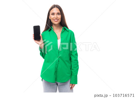 slender young brown-haired female model with brown eyes in a green shirt shows the screen of a slender young brown-haired female model with brown eyes in a green shirt shows the screen of a 103716571