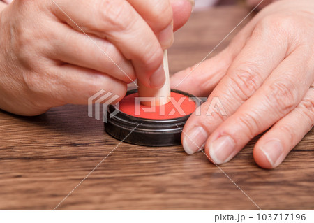 【判子に朱肉をつける女性】 103717196