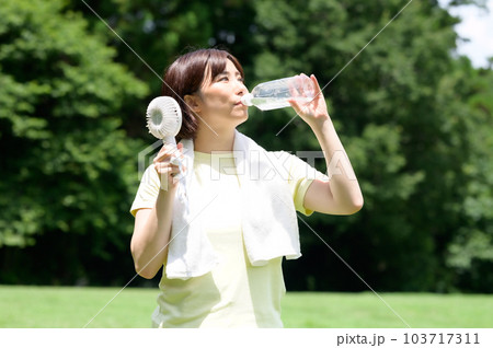 屋外でペットボトルの水を飲む女性 屋外でペットボトルの水を飲む女性 103717311