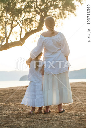 Two lovely sisters, kid and teenage girl standing with their back together Two lovely sisters, kid and teenage girl standing with their back together 103718540
