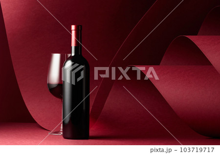Bottle and glass of red wine on a red background. Bottle and glass of red wine on a red background. 103719717