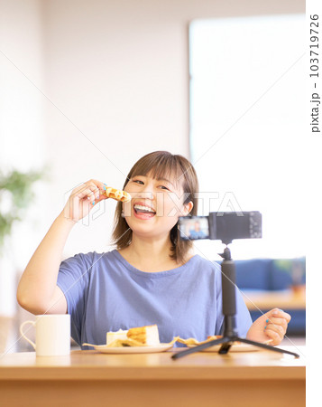 カメラで自分を撮影しながらスイーツを食べる若い女性 カメラで自分を撮影しながらスイーツを食べる若い女性 103719726