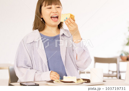 美味しそうな表情でケーキを食べる若い女性 103719731