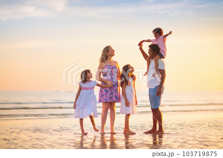 Family walking on tropical beach at sunset Family walking on tropical beach at sunset 103719875