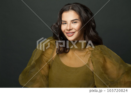 Happy smiling brunette model woman with dark hair against black studio wall background 103720824