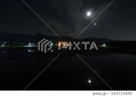 北杜市白州町、薄い雲のベールかかる宵の空に寄添う月と金星を映す水田 103723695