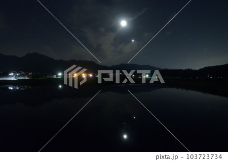 北杜市白州町、薄い雲のベールかかる宵の空に寄添う月と金星を映す水田 103723734