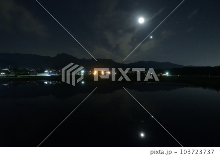 北杜市白州町、薄い雲のベールかかる宵の空に寄添う月と金星を映す水田 103723737