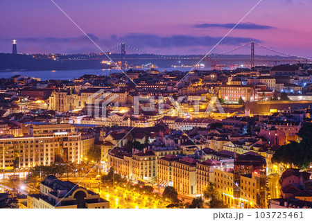 Night view of Lisbon famous view from Miradouro da Senhora do Monte tourist viewpoint of Alfama and Mauraria old city districts, 25th of April Bridge in the evening twilight. Lisbon, Portugal 103725461