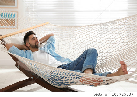 Young man relaxing in hammock at home Young man relaxing in hammock at home 103725937