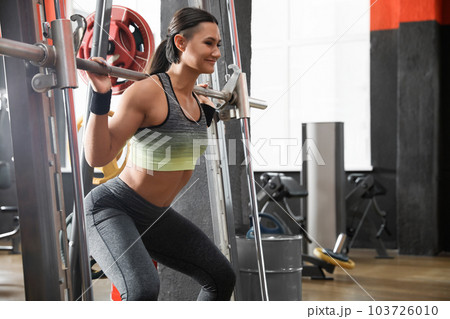 Young woman working out on Smith machine in modern gym 103726010