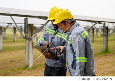 Maintenance engineers team checking solar panels on solar cell farm 103726219