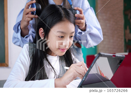 Happy student studying with teacher in classroom at school 103726266