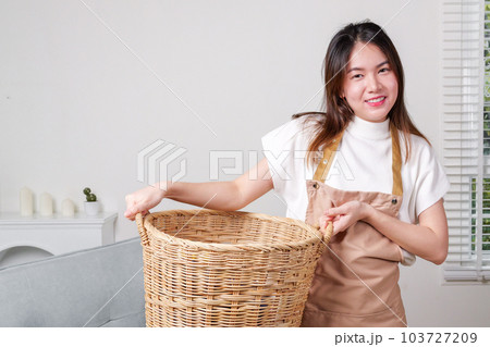 Female housekeeper cleaner taking messy dirty clothes on sofa into basket Female housekeeper cleaner taking messy dirty clothes on sofa into basket 103727209