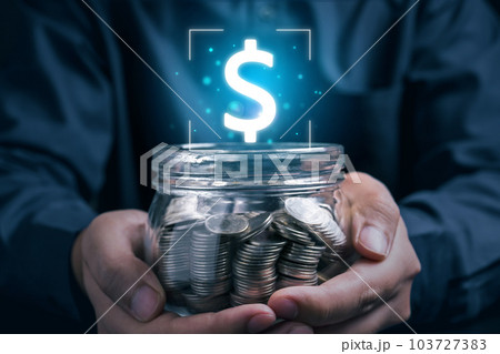 Businessman using laptop and holding jar of coins with dollar sign 103727383