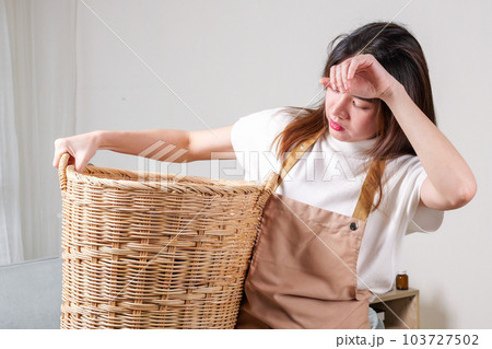 Female housekeeper cleaner taking messy dirty clothes on sofa into basket Female housekeeper cleaner taking messy dirty clothes on sofa into basket 103727502
